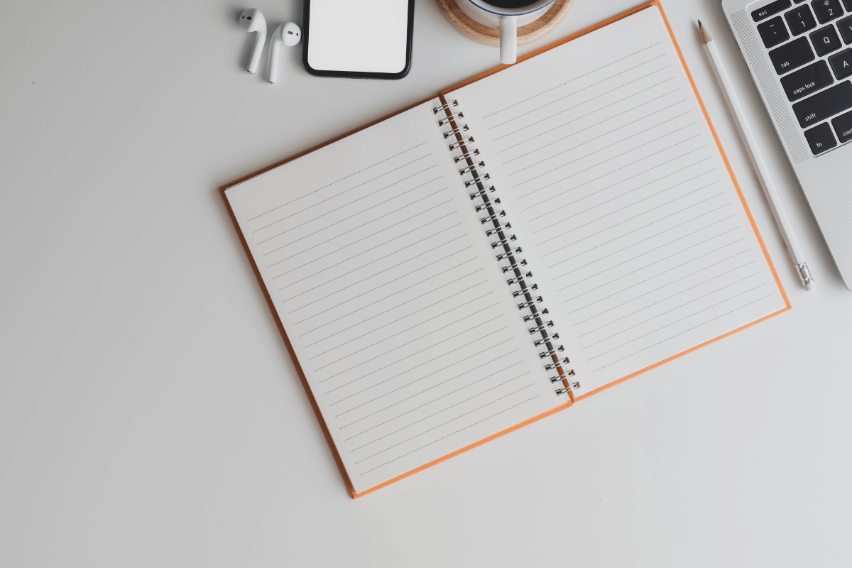 blank notepad on desk beside a laptop
