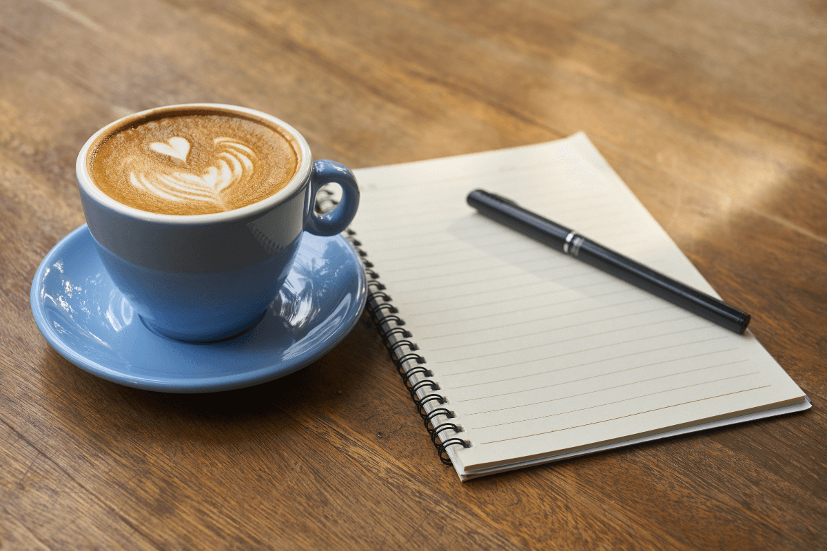 coffee mug and blank notepad on a desk